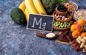 Une main tenant une capsule de magnésium, avec un fond illustrant des aliments riches en magnésium comme des noix, des bananes et des légumes verts.