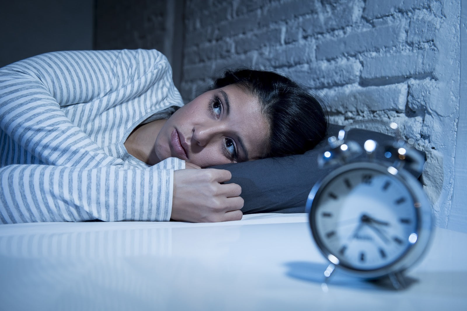 Personne détendue dormant paisiblement sur un oreiller moelleux, après avoir surmonté des troubles du sommeil grâce à nos conseils.